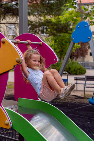 Adorable little girl having fun on a playground in the park.の写真素材