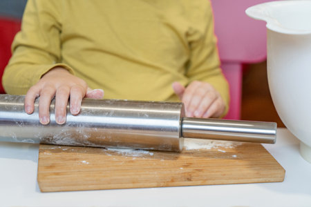 The little hands of the child rock the dough with a rolling pin for the varenyky.の写真素材