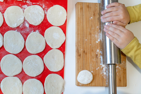The little hands of the child rock the dough with a rolling pin for the varenyky.の写真素材