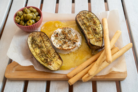 Baked eggplant with cheese, olives and bread sticks on wooden boardの写真素材