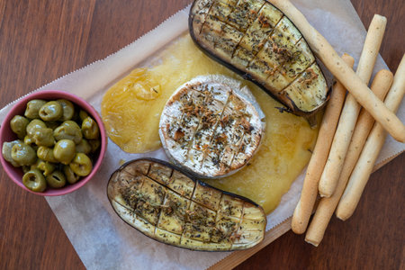 Grilled eggplant with cheese, olives and breadsticks on wooden tableの写真素材