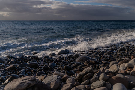 Beautiful seascape with pebble beach and sea waves of Madeira, Portugalの写真素材
