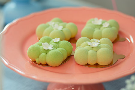 mini green mousse cake with white flowers on pink plate.の写真素材