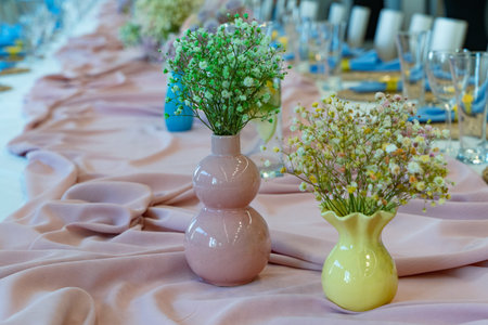 Decorated table of beautiful flowers in vase for wedding or another catered event dinner.