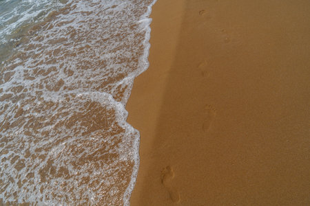 Footprints in the sand on the beach with sea wave, Thailand.の写真素材