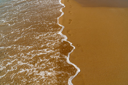 Footprints in the sand on the beach with sea wave, Thailand.の写真素材