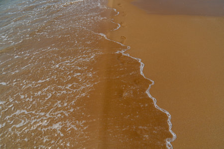 Footprints in the sand on the beach with sea wave, Thailand.の写真素材