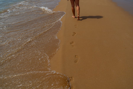 Footprints in the sand on the beach with sea wave, Thailand.の写真素材