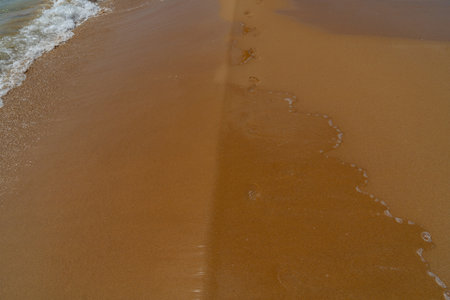 Footprints in the sand on the beach with sea wave, Thailand.の写真素材