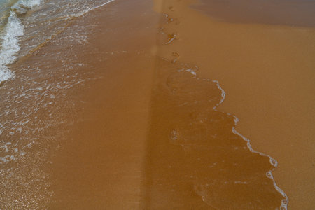 Footprints in the sand on the beach with sea wave, Thailand.の写真素材