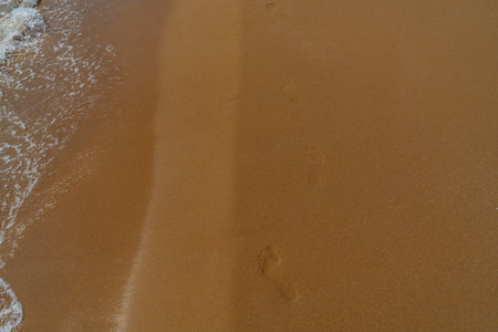 Footprints in the sand on the beach with sea wave, Thailand.の写真素材