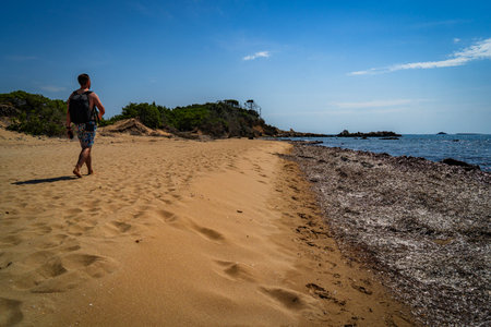 A young man walking on a sandy beach in Ibiza, Spainの写真素材