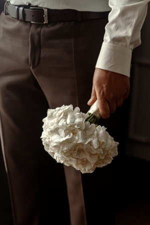 Wedding bouquet of white flowers in the hands of the groomの写真素材
