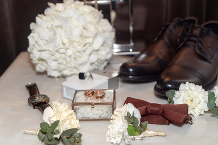 Wedding rings, boutonniere and shoes on the tableの写真素材