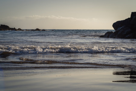 Waves breaking on the rocks on the beach in the evening.