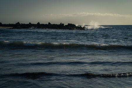 Waves breaking on the rocks on the beach in the evening.の写真素材