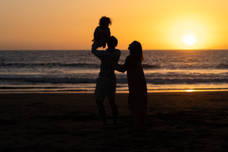 Silhouette of mother and baby on the beach at sunset.の写真素材