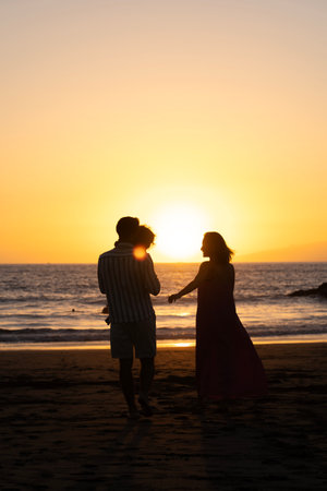 Silhouette of a loving family on the beach at sunset.の写真素材