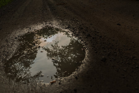 Reflection of the sun in a puddle on the asphalt roadの写真素材