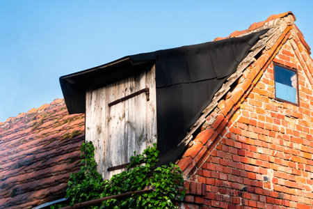Old wooden house with tiled roof and chimney against blue skyの写真素材