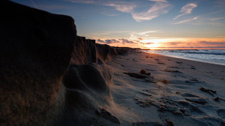 Beautiful sunset on the beach with rocks in the foreground. Long exposure.の写真素材