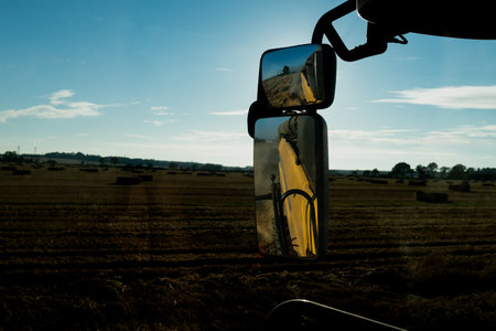 Harvesting of wheat field with combine harvester at sunsetの写真素材