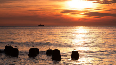 Sunset in the sea with silhouette of a boat on the horizonの写真素材