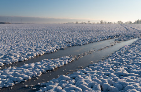 Frozen canal in a snowy field in the Poland at sunrise.の写真素材