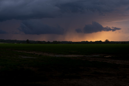 Dramatic stormy sky over green field in the evening.の写真素材
