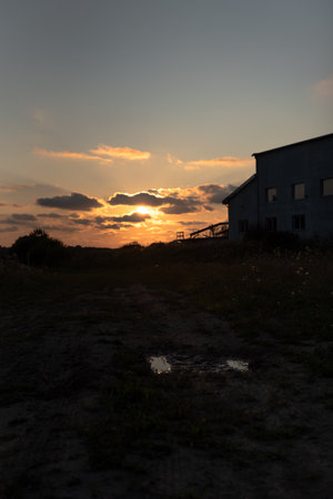 Abandoned factory in the evening with sun setting behind the cloudsの写真素材