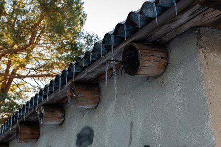 Icicles hanging from the roof of an old houseの写真素材