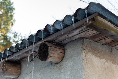 Icicles hanging from the roof of a house in winter.の写真素材