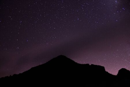 Mountain with a purple star sky and city lightsの写真素材
