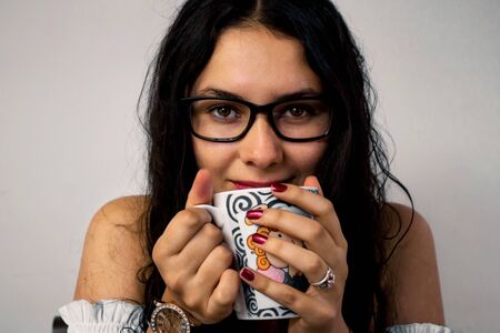 latin girl with glasses drinking coffeeの写真素材