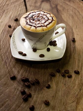 coffee cup latte art made with organic coffee, chocolate and coffee beans on background and on wooden backgroundの写真素材
