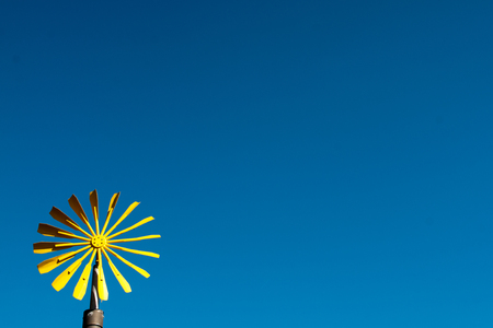 Yellow wind wheel with a blue cloudless skyの写真素材