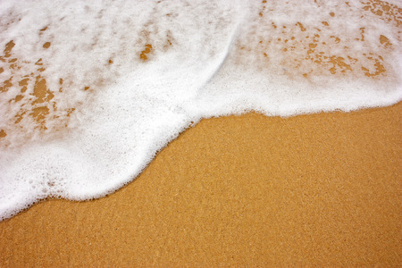 Wave creates a foam that is beautiful to lie on the beach sand