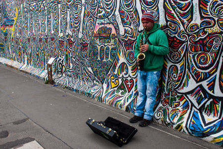 BERLIN - JUN 8: Musician at East Side Gallery on Jun 8, 2013 in Berlin, Germany. It is a 1,3 km long part of original Berlin wall, famous memorial with many grafittis.のeditorial素材