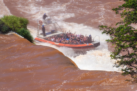 IGUAZU, ARGENTINA - FEB 6, 2015: Tourists in a boat under Iguacu (Iguazu) falls on a border of Brazil and Argentinaのeditorial素材