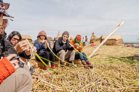 TITICACA, PERU - MAY 15, 2015: Visitors are learning about the reed used for building Uros floating islands, Titicaca lake, Peruのeditorial素材