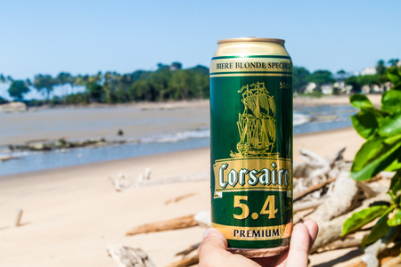 CAYENNE, FRENCH GUIANA - AUGUST 3, 2015: Can of Corsaire beer. This beer brand comes from Guadeloupe. Beach in th background out of focus.のeditorial素材