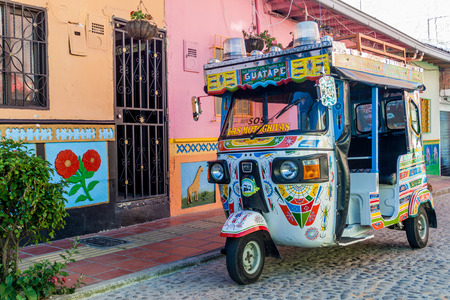GUATAPE, COLOMBIA - SEPTEMBER 2, 2015: Colorful mototaxi (tuk tuk) and decorated houses in Guatape village, Colombiaのeditorial素材