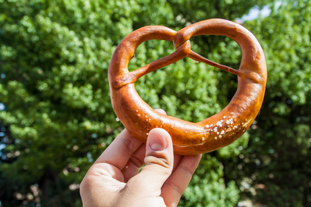 Human hand holds fresh German pretzel (Bretzel)の写真素材
