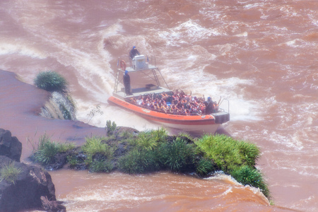 IGUAZU, ARGENTINA - FEB 6, 2015: Tourists in a boat under Iguacu (Iguazu) falls on a border of Brazil and Argentinaのeditorial素材