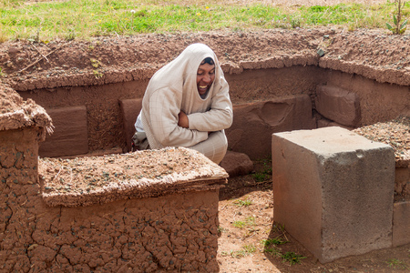 TIWANAKU, BOLIVIA - APRIL 24, 2015: Tourist guide shows the position of bodies in a grave,Tiwanaku ruins, Titicaca region, Bolivia.のeditorial素材