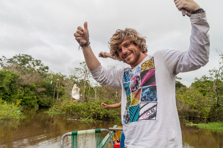 YACUMA, BOLIVIA - MAY 5, 2015: Tourist with a fished piranha on Yacuma river, Boliviaの写真素材