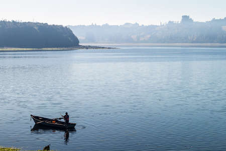 Fisherman in a morning mist on a sea in Castro, Chiloe island, Chile