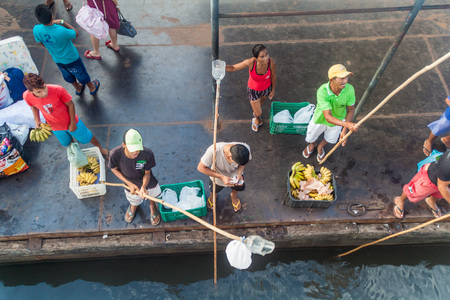 JURUTI, BRAZIL - JUNE 28, 2015: Sellers use a long stick to deliver the goods to passengers of a river boat which is anchored at the pier.のeditorial素材