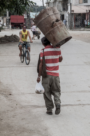 HOLGUIN, CUBA - JAN 28, 2016: Street scene with a man carrying an old barrel.のeditorial素材
