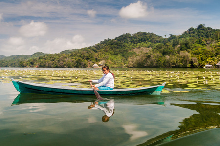 RIO DULCE, GUATEMALA - MARCH 10, 2016: Local indigenous woman paddling across Rio Dulce river, Guatemalaのeditorial素材